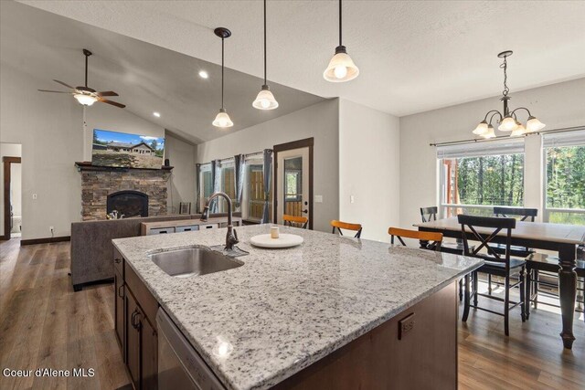 23378 N Prominence Rd, Rathdrum, ID 83858 - kitchen featuring stainless steel dishwasher, dark wood-style flooring, ceiling fan, vaulted ceiling, and a stone fireplace