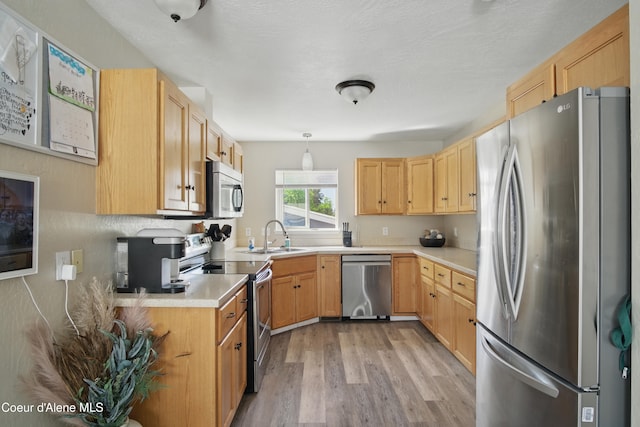 15272 N Stevens St, Rathdrum, ID 83858 - kitchen with appliances with stainless steel finishes, a sink, light wood finished floors, light countertops, and pendant lighting
