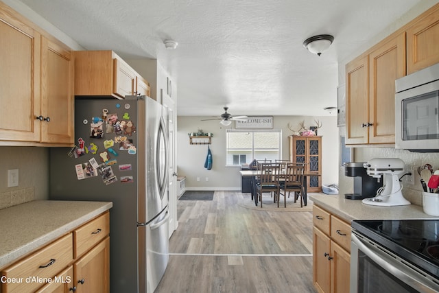 15272 N Stevens St, Rathdrum, ID 83858 - kitchen featuring stainless steel appliances, light countertops, ceiling fan, light wood finished floors, and decorative backsplash