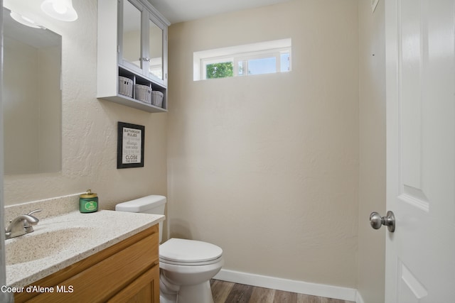 15272 N Stevens St, Rathdrum, ID 83858 - half bathroom featuring wood finished floors, toilet, vanity, and baseboards