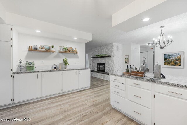 16 Beers Humbird Rd, Sagle, ID 83860 - kitchen with white cabinets, a fireplace, a chandelier, light wood-style floors, and recessed lighting