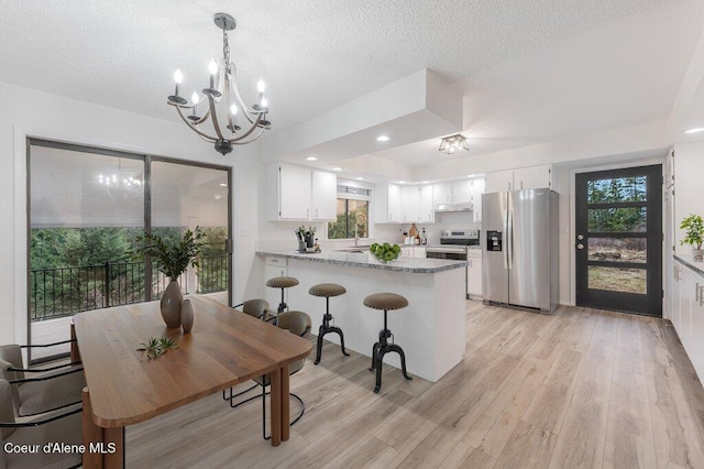 16 Beers Humbird Rd, Sagle, ID 83860 - kitchen featuring appliances with stainless steel finishes, a chandelier, a peninsula, light wood finished floors, and a textured ceiling