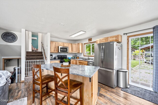 8525 W Nevada St, Rathdrum, ID 83858 - kitchen with stainless steel appliances, dark wood-type flooring, a sink, light brown cabinetry, and a breakfast bar