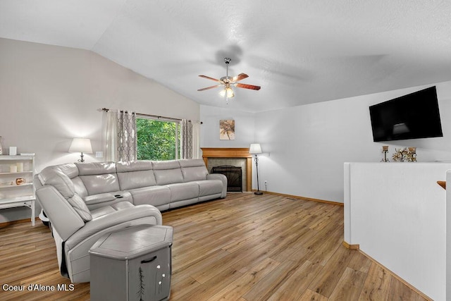 5735 E Steamboat Bnd, Post Falls, ID 83854 - living room with vaulted ceiling, a ceiling fan, light wood-type flooring, baseboards, and a glass covered fireplace