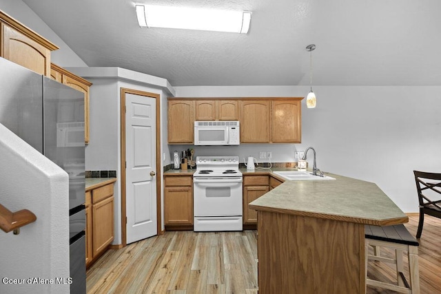 5735 E Steamboat Bnd, Post Falls, ID 83854 - kitchen with white appliances, a peninsula, a sink, light wood finished floors, and a kitchen bar
