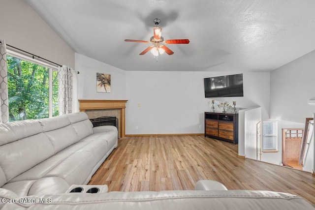 5735 E Steamboat Bnd, Post Falls, ID 83854 - living area with wood finished floors, vaulted ceiling, a ceiling fan, a tiled fireplace, and baseboards