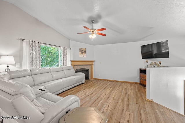 5735 E Steamboat Bnd, Post Falls, ID 83854 - living area with lofted ceiling, light wood-style flooring, ceiling fan, a tiled fireplace, and baseboards