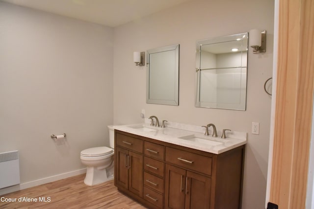 574 Parkside Rd, Plummer, ID 83851 - bathroom featuring double vanity, toilet, wood finished floors, baseboards, and radiator