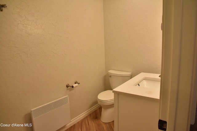 574 Parkside Rd, Plummer, ID 83851 - half bath featuring vanity, toilet, wood finished floors, a textured wall, and radiator heating unit