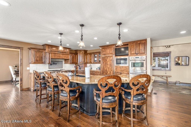 4987 S Bay Pointe Way, Coeur Dalene, ID 83814 - kitchen featuring built in microwave, baseboards, brown cabinets, decorative backsplash, and dark wood-style flooring