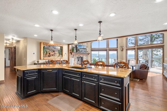 4987 S Bay Pointe Way, Coeur Dalene, ID 83814 - kitchen with a sink, dark cabinets, a textured ceiling, hardwood / wood-style floors, and open floor plan