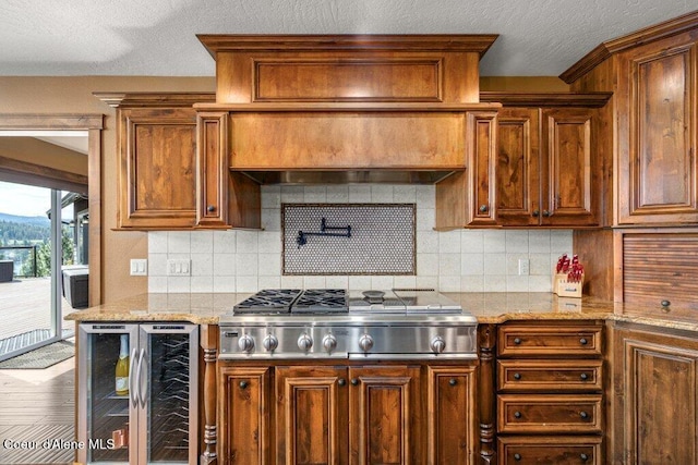 4987 S Bay Pointe Way, Coeur Dalene, ID 83814 - kitchen featuring beverage cooler, stainless steel gas cooktop, brown cabinets, tasteful backsplash, and a textured ceiling