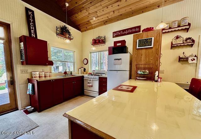 22767 Spruce Ln, Lewiston, ID 83501 - kitchen featuring white appliances, lofted ceiling, wood ceiling, light countertops, and hanging light fixtures