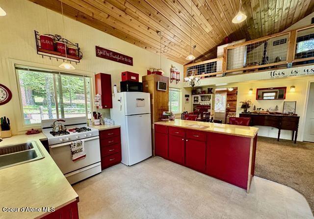 22767 Spruce Ln, Lewiston, ID 83501 - kitchen featuring red cabinetry, white appliances, high vaulted ceiling, wooden ceiling, and light countertops