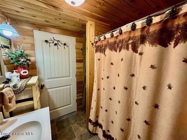 22767 Spruce Ln, Lewiston, ID 83501 - bathroom featuring wood ceiling, wooden walls, and a shower with shower curtain