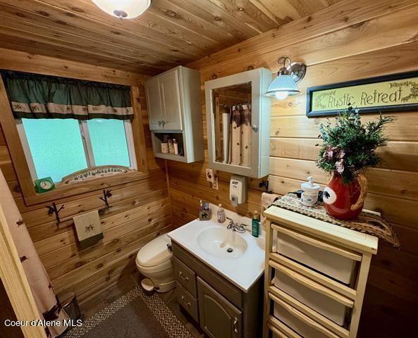 22767 Spruce Ln, Lewiston, ID 83501 - bathroom featuring wood walls, vanity, toilet, and wood ceiling