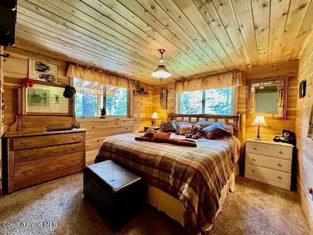 22767 Spruce Ln, Lewiston, ID 83501 - bedroom featuring wooden walls, wood ceiling, and light colored carpet