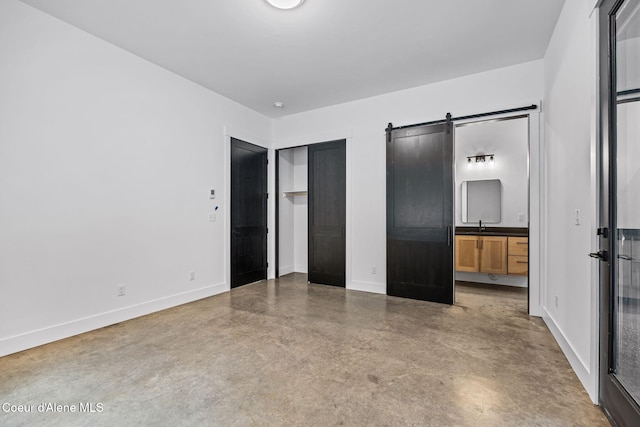 541 N Idaho Club Dr, Sandpoint, ID 83864 - unfurnished bedroom featuring finished concrete flooring, a barn door, baseboards, ensuite bath, and a sink