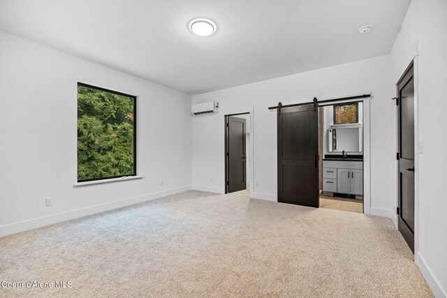 541 N Idaho Club Dr, Sandpoint, ID 83864 - unfurnished bedroom with a wall unit AC, a barn door, light colored carpet, and baseboards