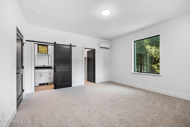 541 N Idaho Club Dr, Sandpoint, ID 83864 - unfurnished bedroom with a wall unit AC, a barn door, baseboards, and light carpet