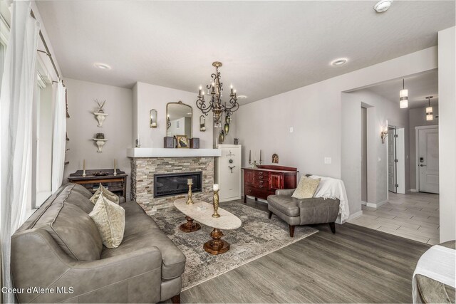 21367 E Acadia Ct, Liberty Lake, WA 99019 - living area featuring wood finished floors, a chandelier, a stone fireplace, and baseboards