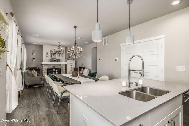 21367 E Acadia Ct, Liberty Lake, WA 99019 - kitchen with a sink, dark wood-style floors, a stone fireplace, white cabinets, and a kitchen island with sink
