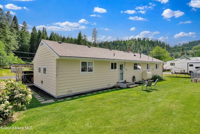 2040 Washington Ave, Saint Maries, ID 83861 - rear view of property featuring a lawn, a chimney, roof with shingles, and a view of trees