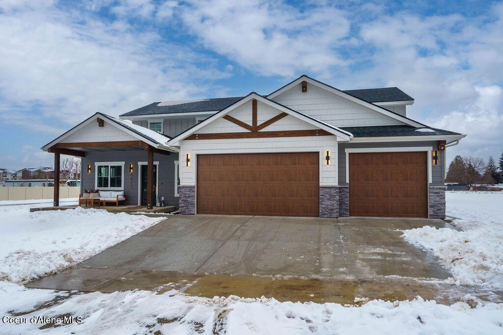 4536 E Savea Ln, Post Falls, ID 83854 - view of front facade featuring an attached garage, stone siding, covered porch, and concrete driveway