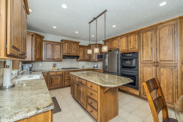 620 N Chisholm Ct, Post Falls, ID 83854 - kitchen with appliances with stainless steel finishes, under cabinet range hood, brown cabinetry, light stone counters, and decorative backsplash