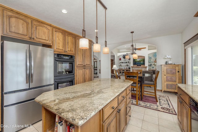 620 N Chisholm Ct, Post Falls, ID 83854 - kitchen featuring black appliances, arched walkways, light stone counters, light tile patterned flooring, and brown cabinetry
