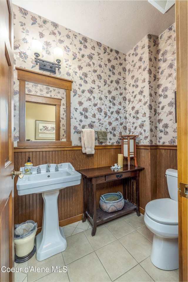 620 N Chisholm Ct, Post Falls, ID 83854 - half bath with wallpapered walls, wainscoting, a textured ceiling, and tile patterned flooring