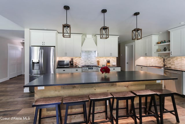 245 Lost Creek Ln, Priest River, ID 83856 - kitchen with appliances with stainless steel finishes, dark countertops, custom range hood, open shelves, and decorative backsplash
