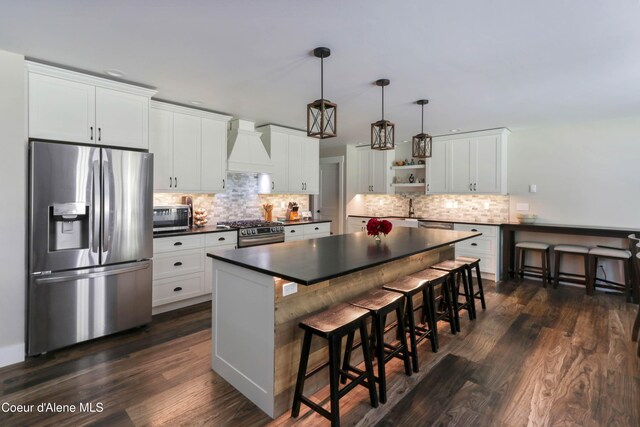 245 Lost Creek Ln, Priest River, ID 83856 - kitchen featuring stainless steel appliances, dark countertops, premium range hood, open shelves, and a breakfast bar