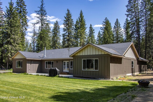 245 Lost Creek Ln, Priest River, ID 83856 - rear view of house with french doors, an outdoor fire pit, a shingled roof, a lawn, and board and batten siding