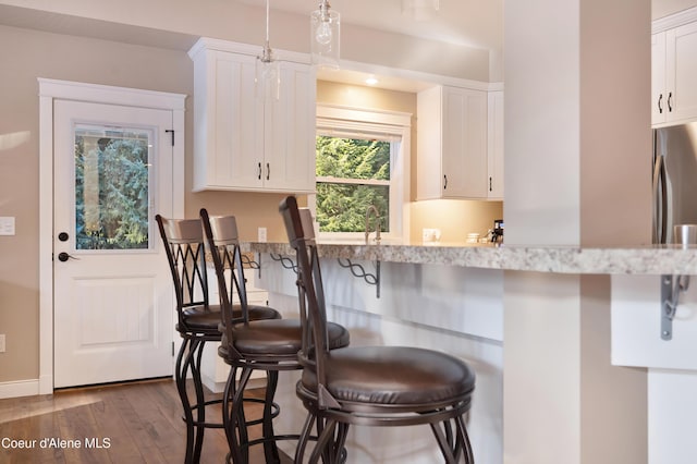 13 Park Dr, Spirit Lake, ID 83869 - kitchen featuring dark wood finished floors, a breakfast bar, white cabinetry, light countertops, and freestanding refrigerator