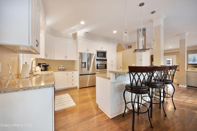 13 Park Dr, Spirit Lake, ID 83869 - kitchen with appliances with stainless steel finishes, exhaust hood, a sink, a kitchen breakfast bar, and light wood finished floors