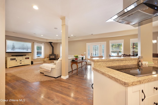 13 Park Dr, Spirit Lake, ID 83869 - kitchen featuring a wood stove, ventilation hood, hardwood / wood-style floors, open floor plan, and black electric stovetop