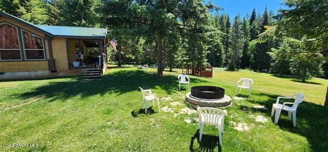 229 Henderson Lp, Kamiah, ID 83536 - view of grassy yard with a fire pit, a porch, and a forest view