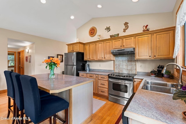 9307 Lakeshore Dr, Sagle, ID 83860 - kitchen with stainless steel appliances, under cabinet range hood, a breakfast bar, a center island, and light wood-style floors