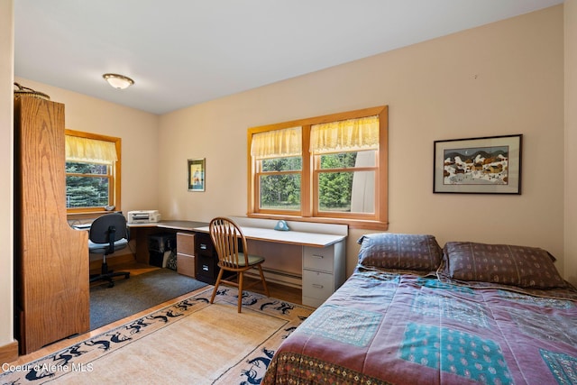 9307 Lakeshore Dr, Sagle, ID 83860 - bedroom featuring an office area, wood finished floors, and a baseboard heating unit