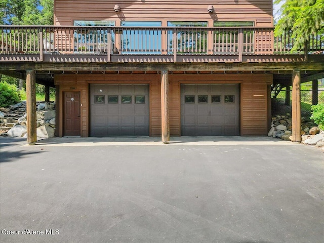 106 Stewart Dr, Blanchard, ID 83804 - rear view of property featuring a garage, a wooden deck, and driveway