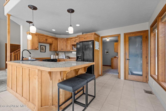 106 Stewart Dr, Blanchard, ID 83804 - kitchen with black fridge with ice dispenser, a peninsula, a sink, light tile patterned flooring, and light countertops