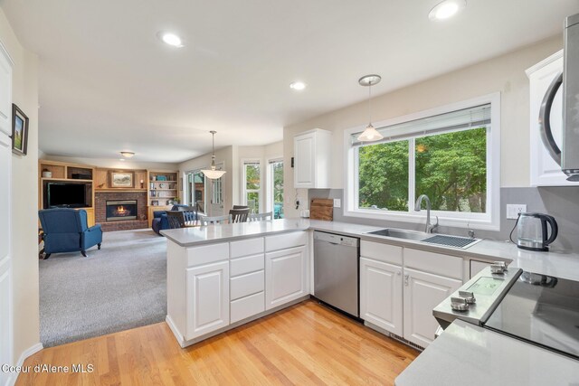 4950 E Frazier Dr, Post Falls, ID 83854 - kitchen featuring stainless steel dishwasher, a sink, open floor plan, a peninsula, and white cabinetry