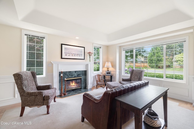 4950 E Frazier Dr, Post Falls, ID 83854 - living area featuring a raised ceiling, a high end fireplace, a decorative wall, a wainscoted wall, and light wood-style flooring
