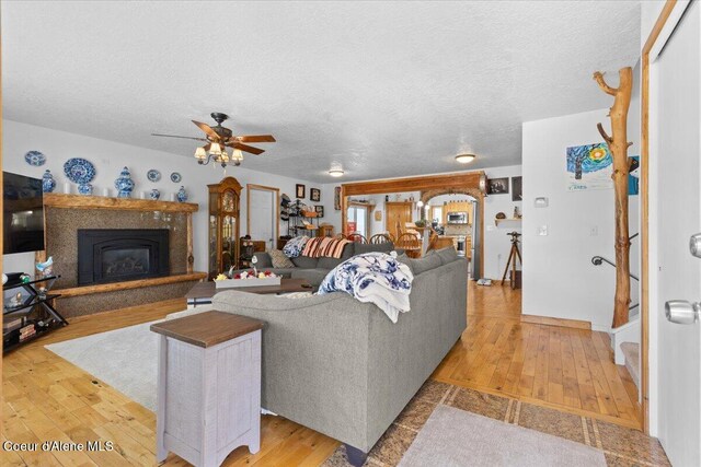 9670 N Meadow Way, Hayden, ID 83835 - living area with a ceiling fan, light wood-style floors, a glass covered fireplace, and a textured ceiling