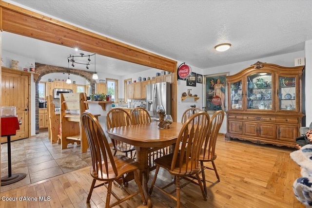 9670 N Meadow Way, Hayden, ID 83835 - dining space featuring light wood finished floors, a textured ceiling, and arched walkways