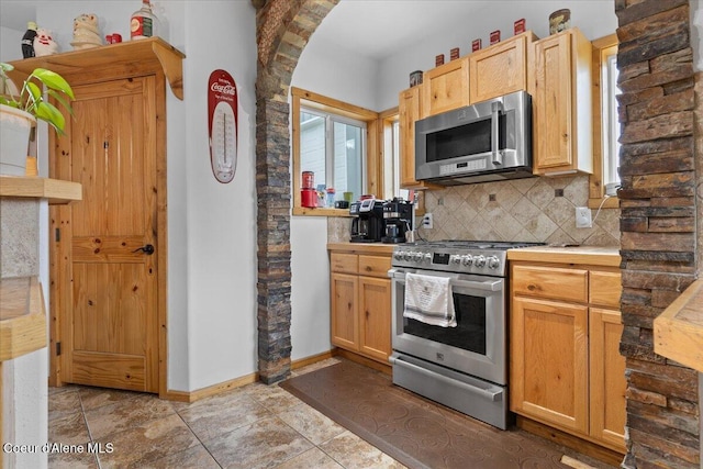 9670 N Meadow Way, Hayden, ID 83835 - kitchen featuring appliances with stainless steel finishes, tasteful backsplash, light countertops, arched walkways, and baseboards