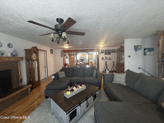 9670 N Meadow Way, Hayden, ID 83835 - living area with wood finished floors, a ceiling fan, a textured ceiling, and a fireplace