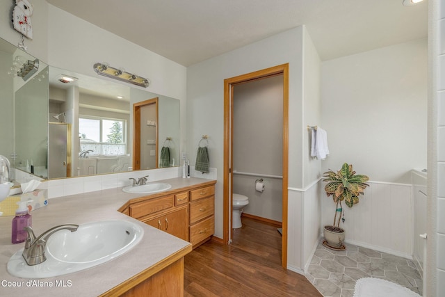 8846 N Clarkview Pl, Hayden, ID 83835 - full bathroom with double vanity, a shower stall, wood finished floors, and a wainscoted wall