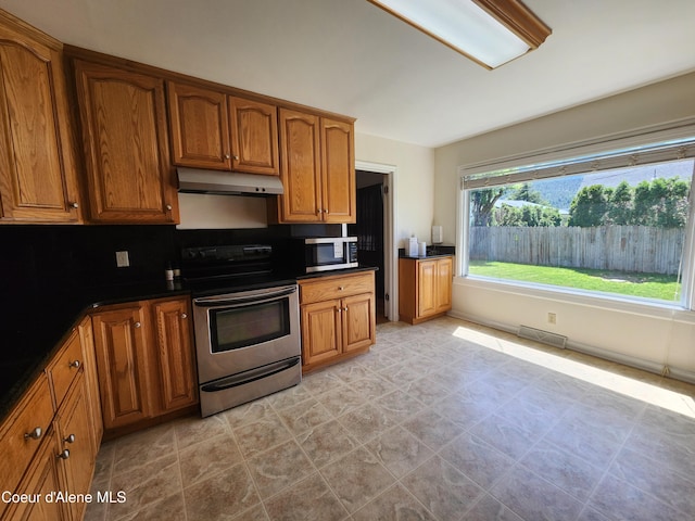 607 W Riverside Ave, Kellogg, ID 83837 - kitchen featuring appliances with stainless steel finishes, under cabinet range hood, brown cabinets, and dark countertops